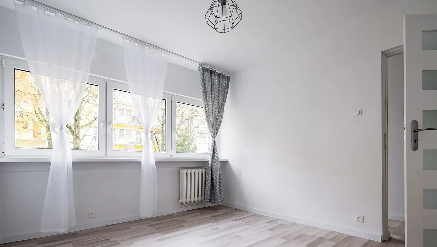 Una habitación vacía con muchas ventanas y cortinas.
