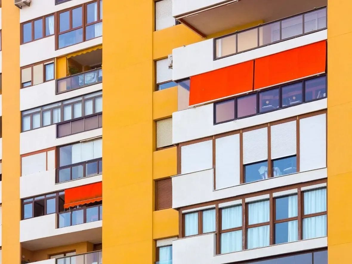 Un edificio amarillo con muchas ventanas y balcones.