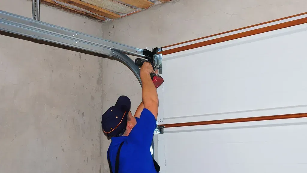 Un hombre está instalando una puerta de garaje en un garaje.
