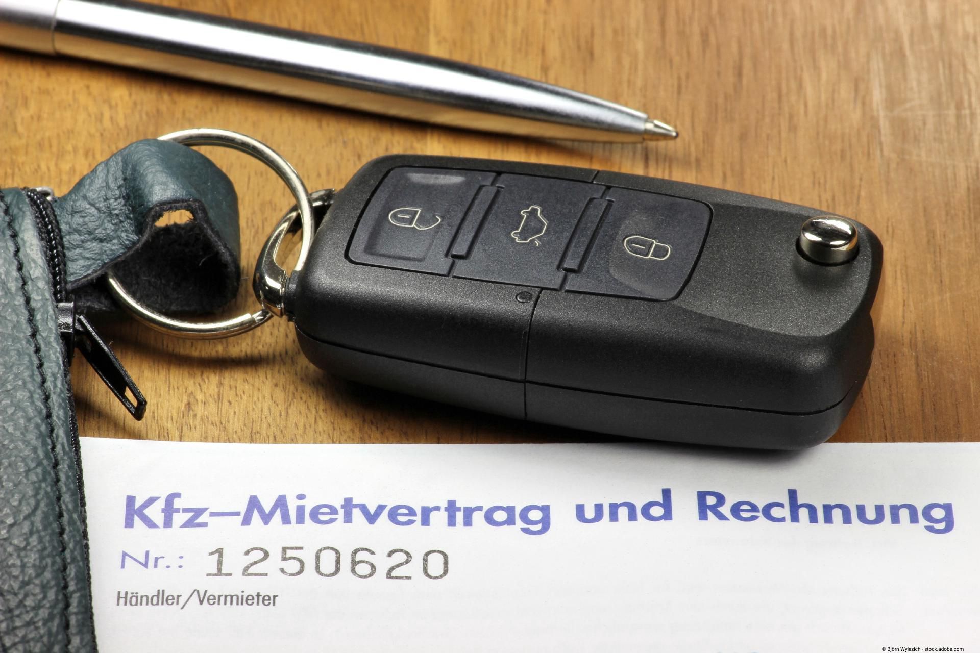 Auf einem Schreibtisch liegt ein Kugelschreiber,ein Autoschlüssel und darunter ein KFZ-Mietvertrag