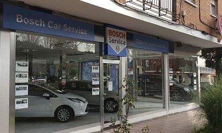 Un taller de Bosch Car Service con ventanales que van desde el suelo hasta el techo, donde se exhiben coches y hay letreros azules.