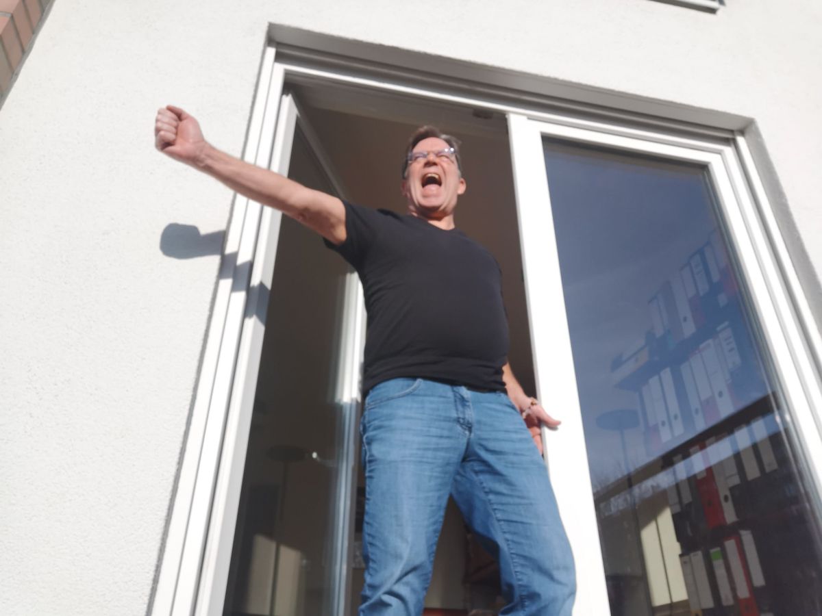Ein Mann steht mit ausgestreckten Armen vor einer Tür