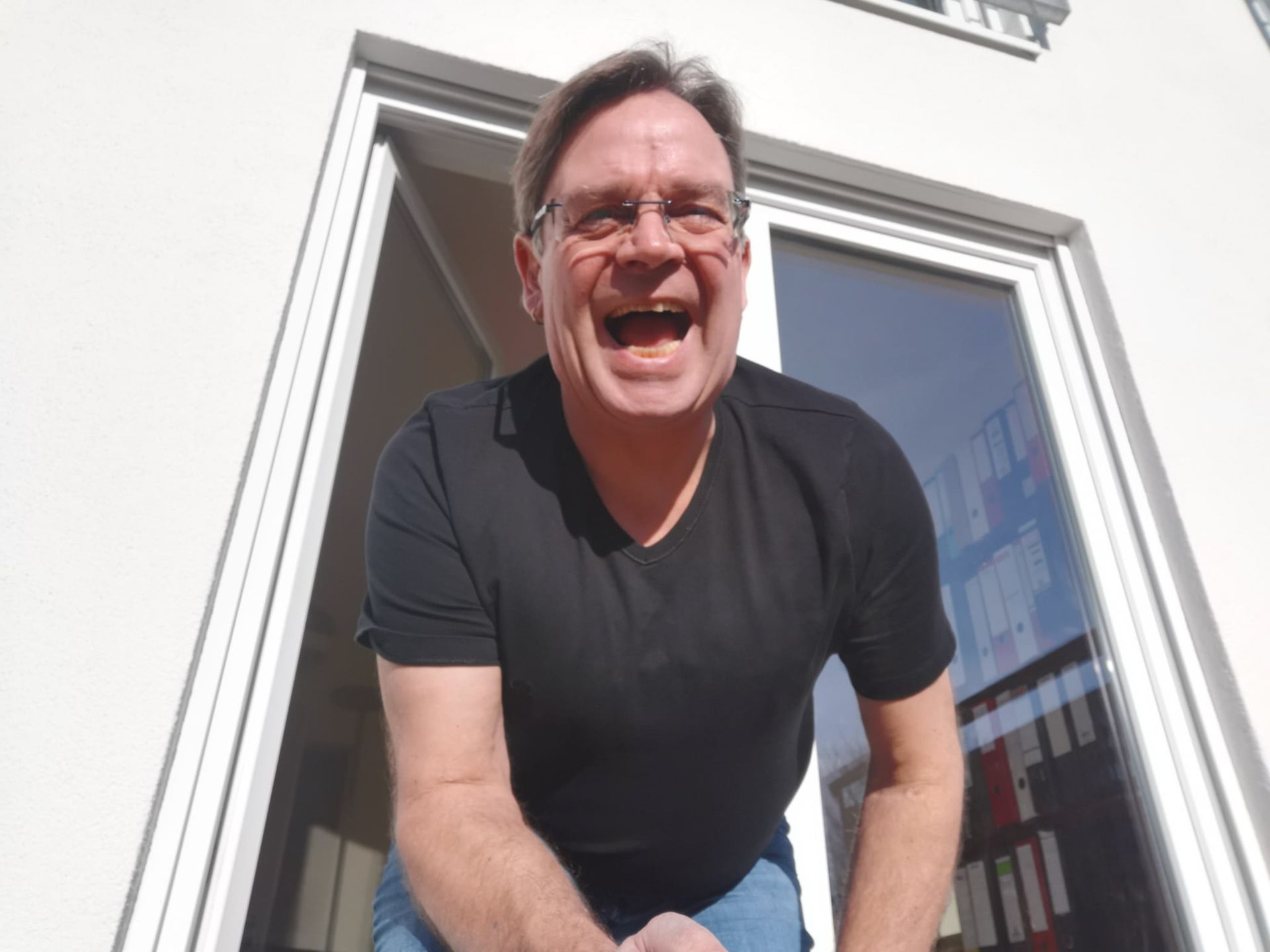 Ein Mann mit Brille und schwarzem Hemd lacht