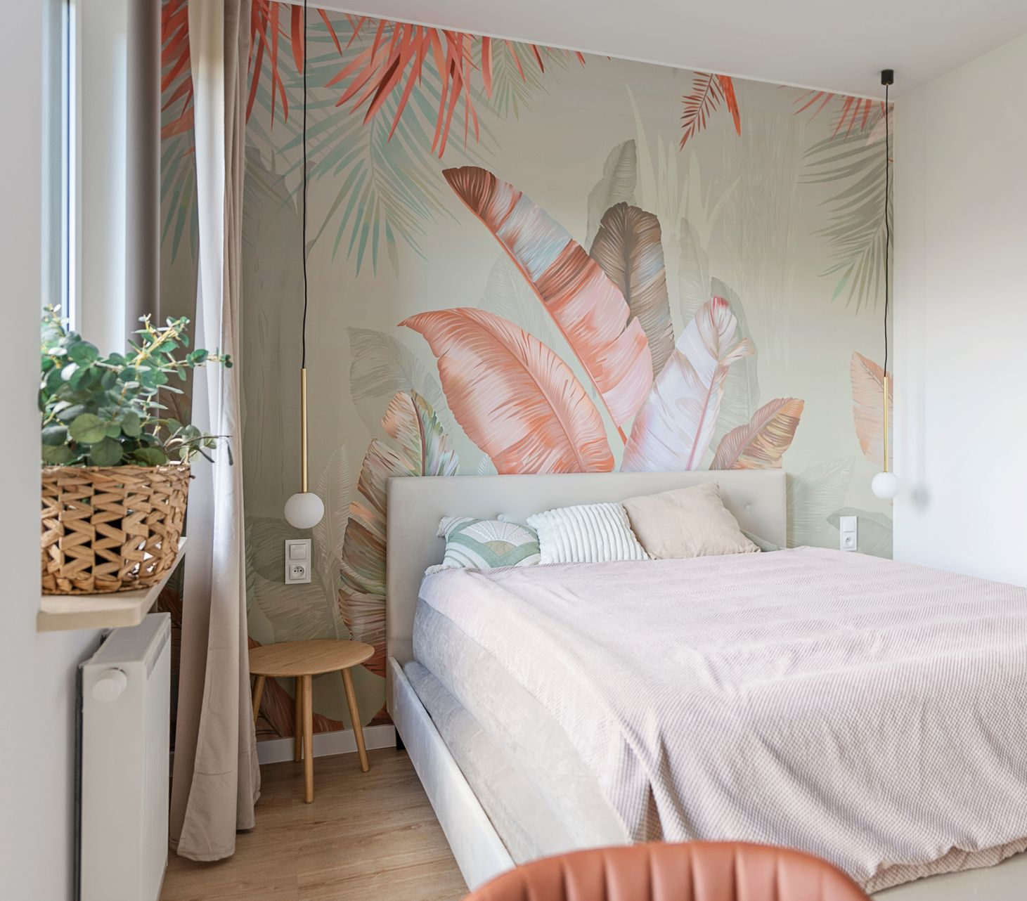 Chambre cosy avec fresque tropicale, lit, table de chevet et décoration aux tons neutres et doux