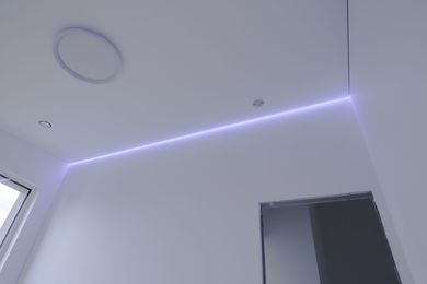 Plafond blanc avec éclairage LED violet et une porte en dessous