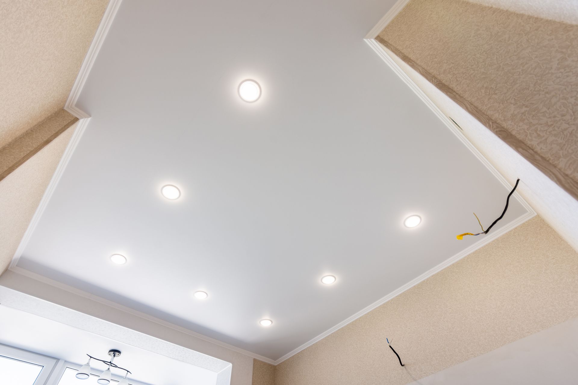 Plafond avec spots encastrés dans une pièce beige, vu d'en bas.