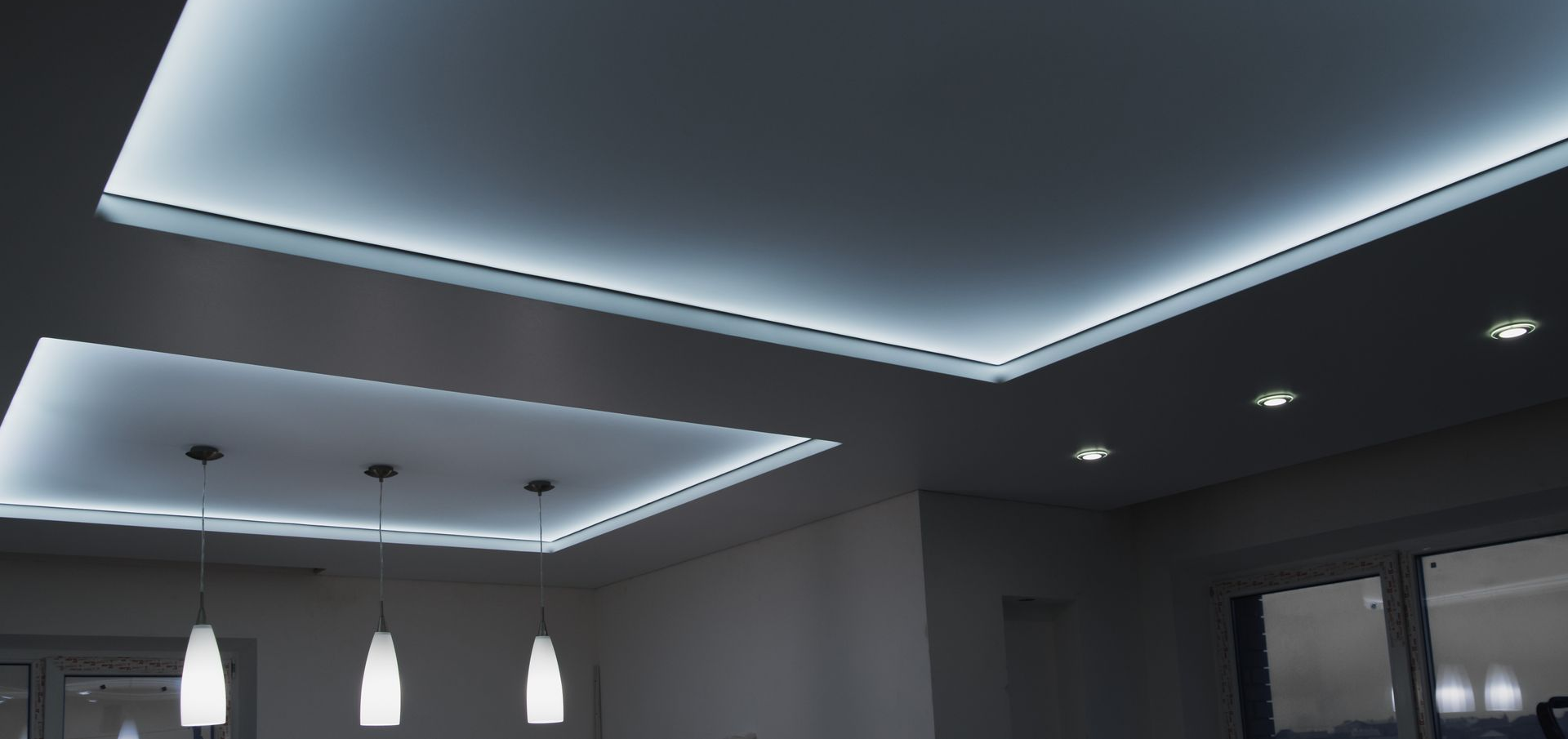 Plafond de salon moderne avec éclairage encastré et suspensions dans un intérieur gris
