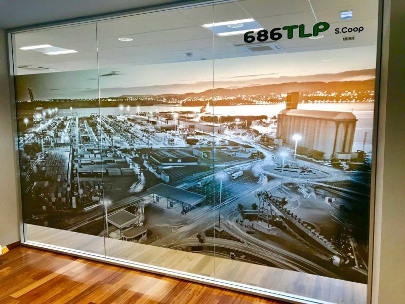 Ventana de oficina con un gran mural en blanco y negro de un paisaje urbano. El texto superior dice