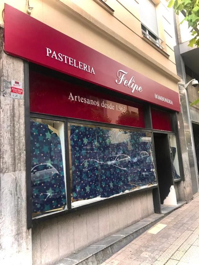 Pastelería Felipe, con un toldo rojo en la fachada. Los escaparates están cubiertos con una vitrina con estampados azules.
