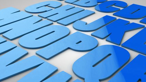 Letras del alfabeto 3D de color azul esparcidas sobre un fondo blanco.