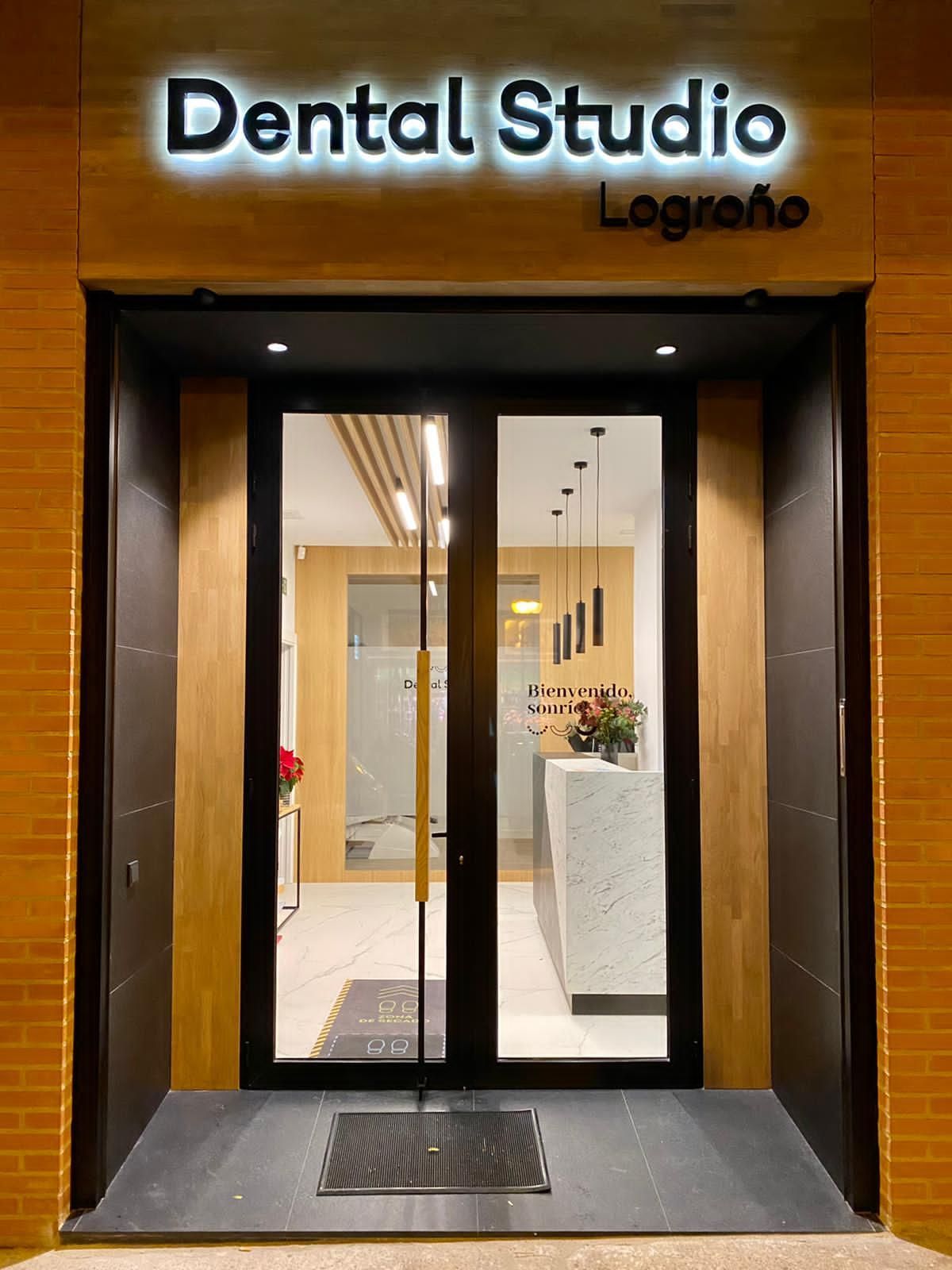 Estudio Dental en Logroño: puertas de cristal, cartel luminoso encima, exterior de ladrillo visto, interior moderno visible.