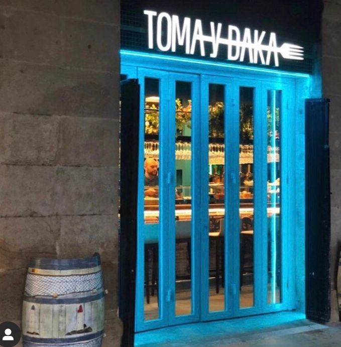 Entrada del restaurante con puertas iluminadas de azul y un cartel que dice 