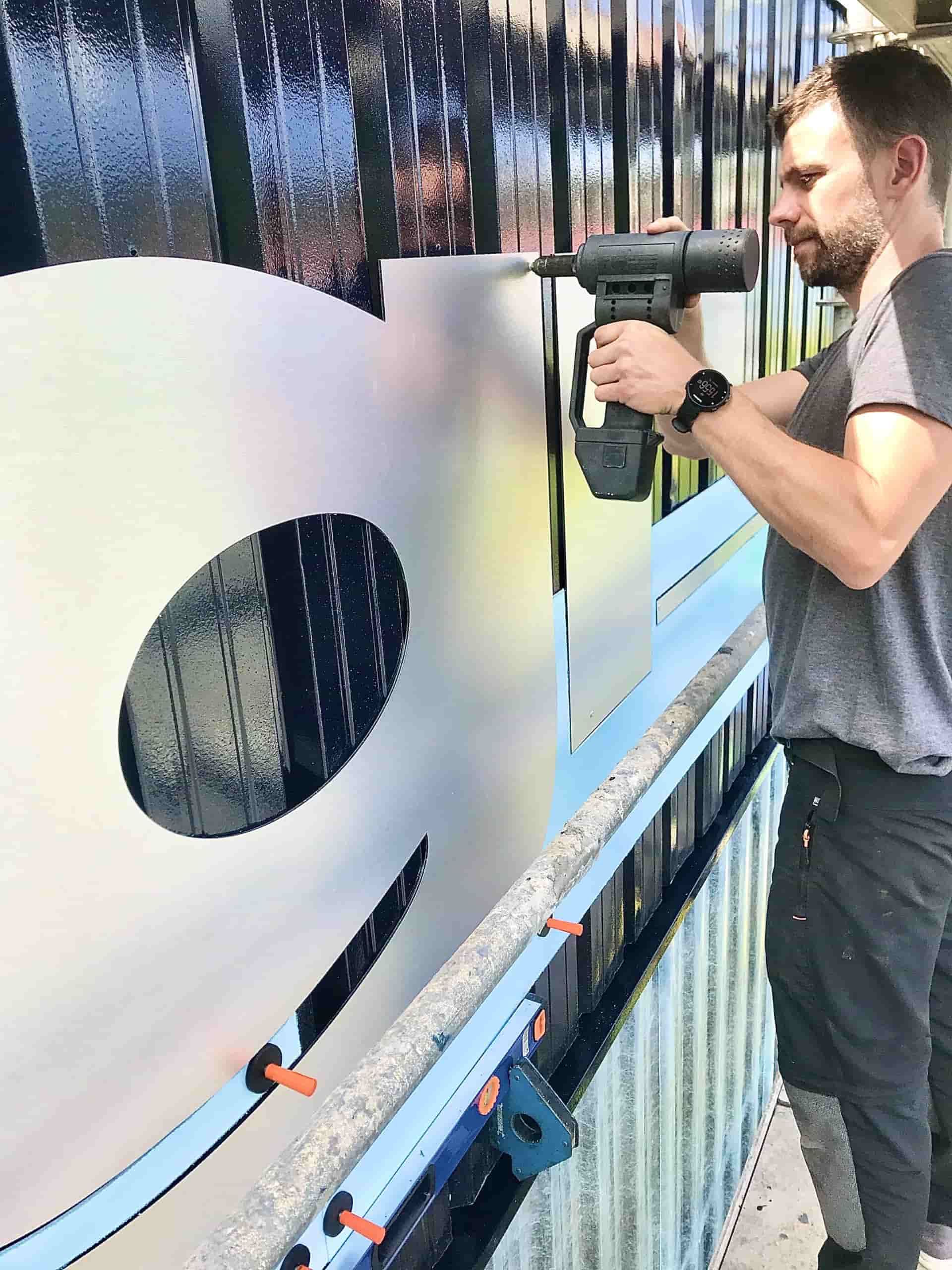 Hombre usando una herramienta para trabajar en una gran obra abstracta con una forma parcial de