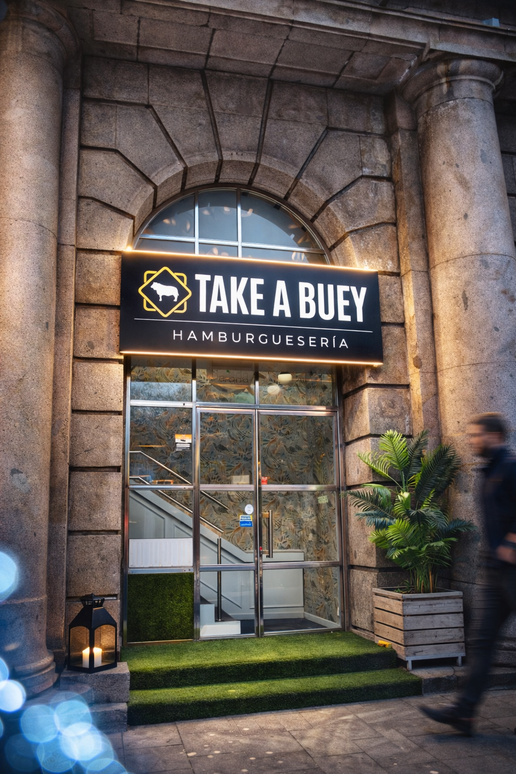 Entrada de la clínica DENTAL OREKA con cartel azul sobre puerta de vidrio, fachada de ladrillo y gráfico circular abstracto en la ventana.