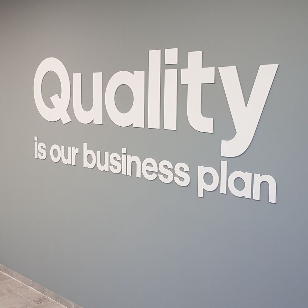 Ein Schild an der Wand mit der Aufschrift „Qualität ist unser Geschäftsplan“
