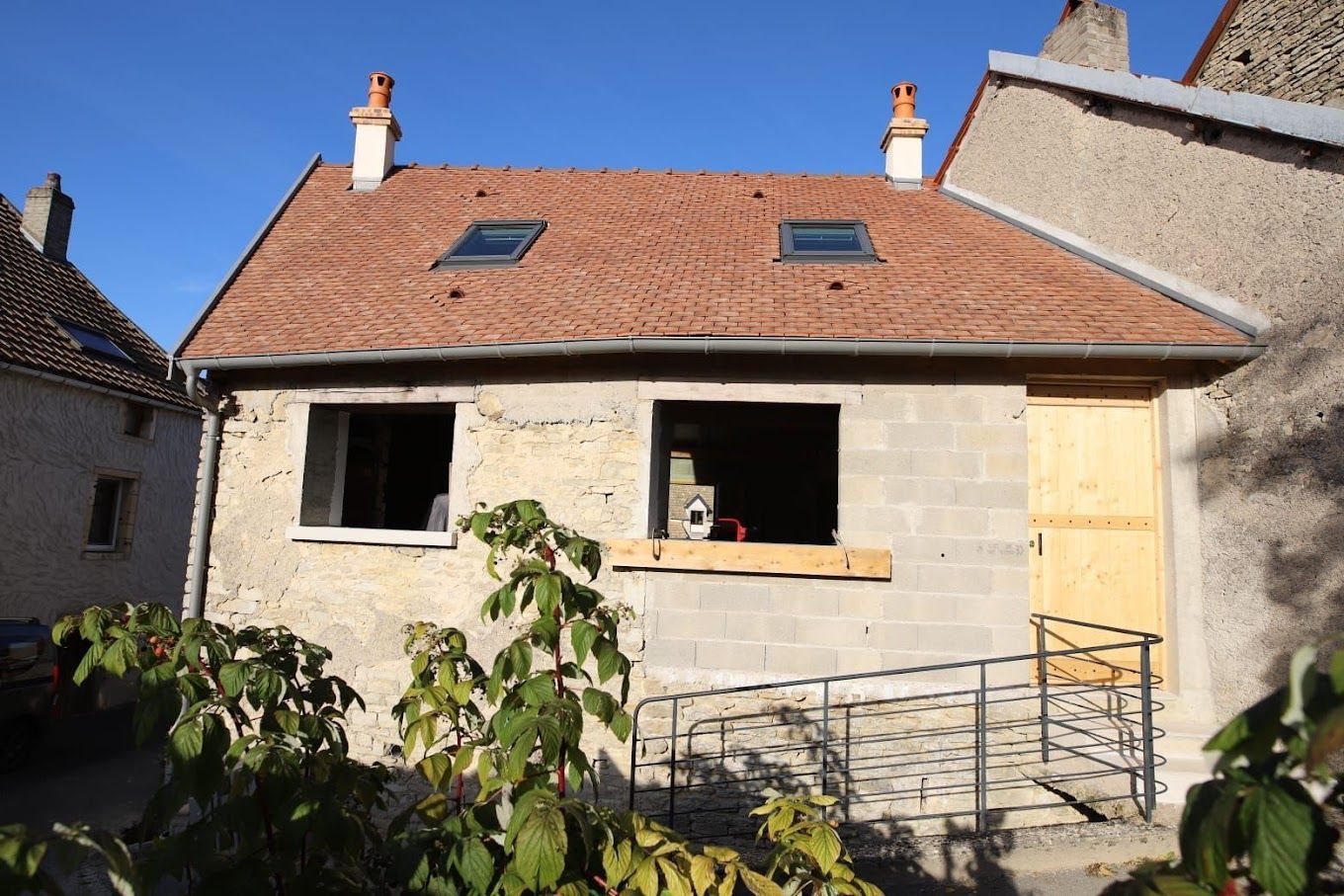 Maison mitoyenne avec toiture en tuile, fenêtres de toit et murs à nu.