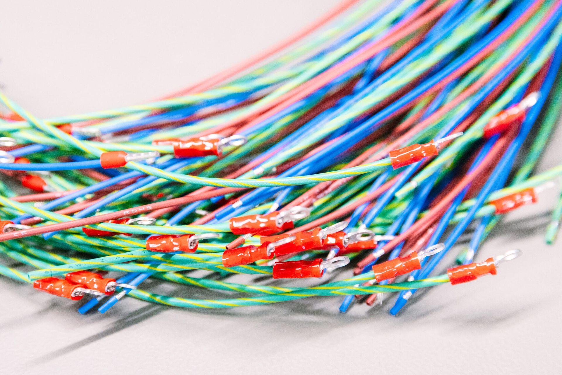 Faisceau de câbles à fibres optiques multicolores avec des connecteurs rouges sur une surface blanche