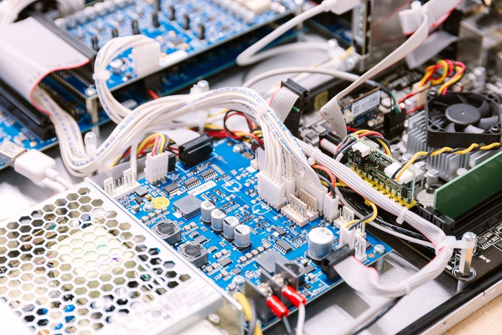 Gros plan sur une carte de circuit imprimé d'ordinateur avec des câbles blancs, des composants bleus et des ventilateurs
