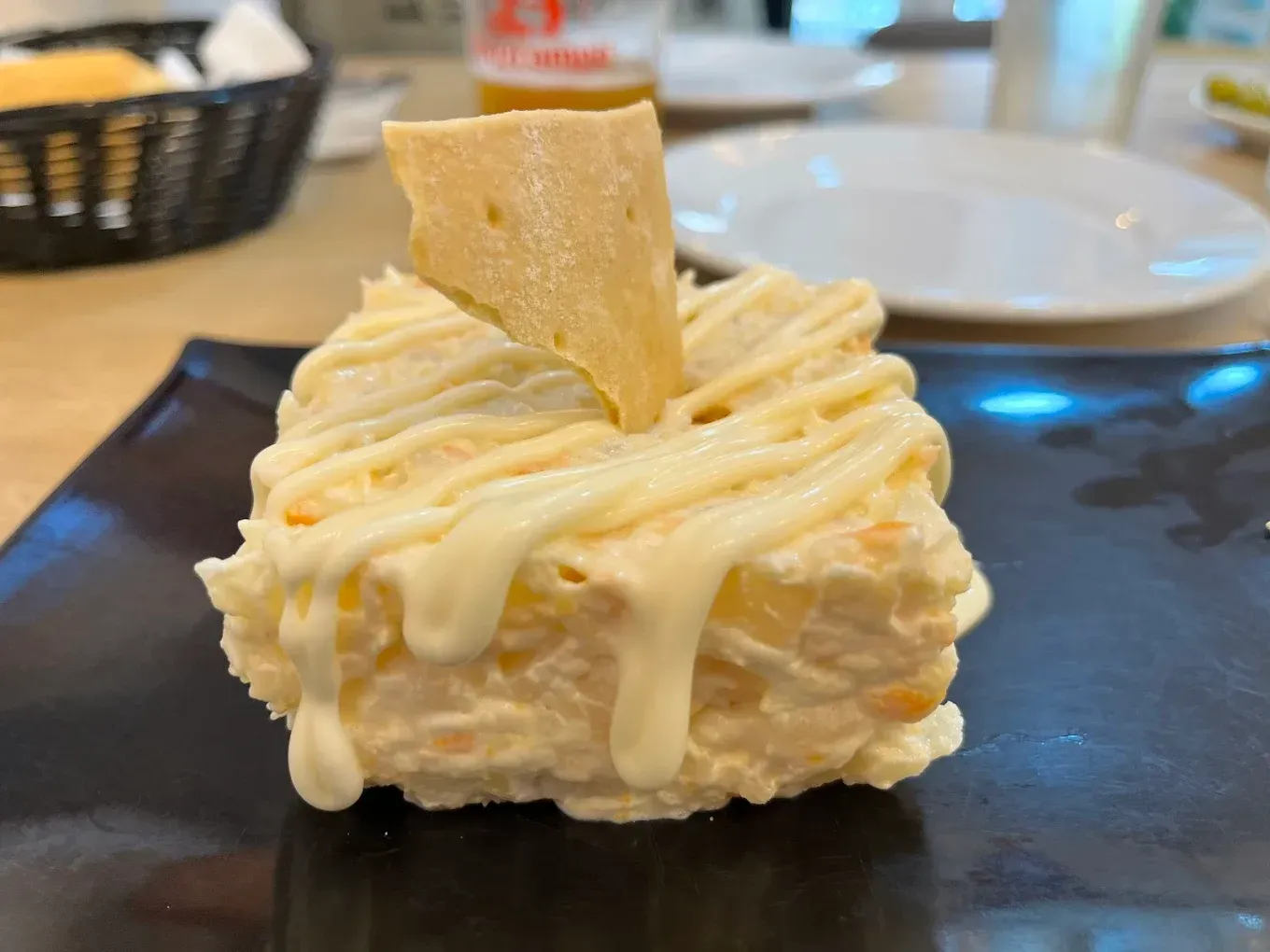 Ensalada de patatas con mayonesa y una galleta en un plato negro.