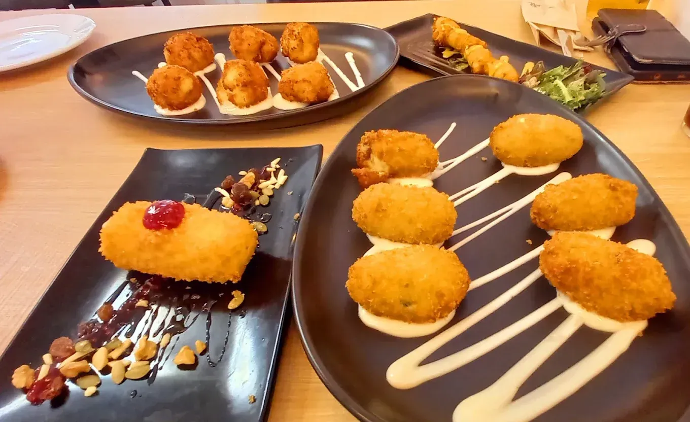 Platos de diversos alimentos fritos con salsas para mojar sobre una mesa.