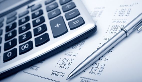 Calculadora y bolígrafo sobre un documento lleno de números financieros.