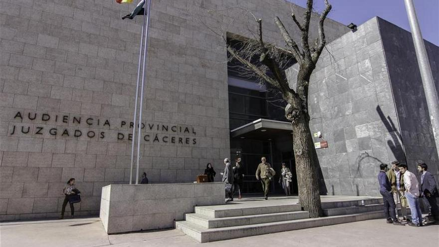 Exterior de la Audiencia Provincial de Cáceres, España. Gente entrando. Fachada de piedra, árbol.