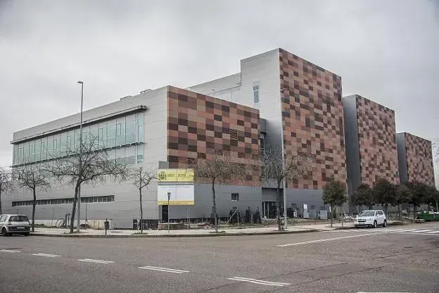 Edificio moderno con fachada a cuadros grises y marrones, cielo nublado.