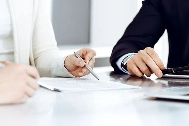 Dos personas vestidas de negocios revisando un documento en una mesa.
