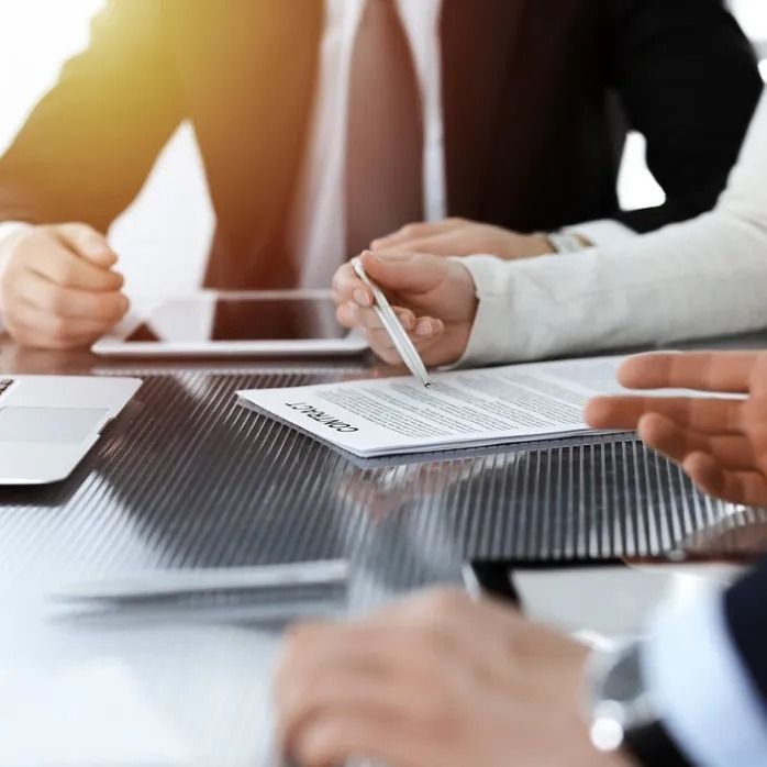 Gente de negocios en una mesa, revisando un contrato con un bolígrafo.