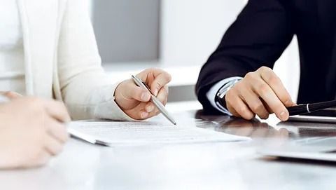 Dos empresarios revisando un documento, uno de ellos señalando con un bolígrafo.
