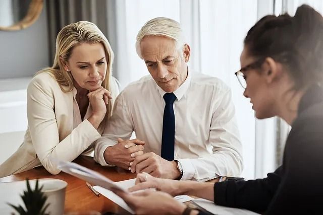 Pareja revisa documentos con un profesional; parecen preocupados.