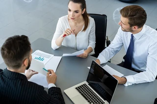 Compañeros de negocios en una reunión: revisando gráficos y documentos en una mesa.