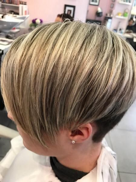 Une femme vue de 3/4 avec des cheveux très courts et blonds