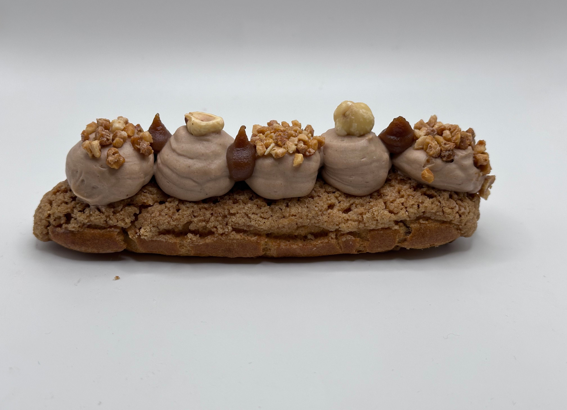 Une pâtisserie avec glaçage au chocolat et noix sur une surface blanche.