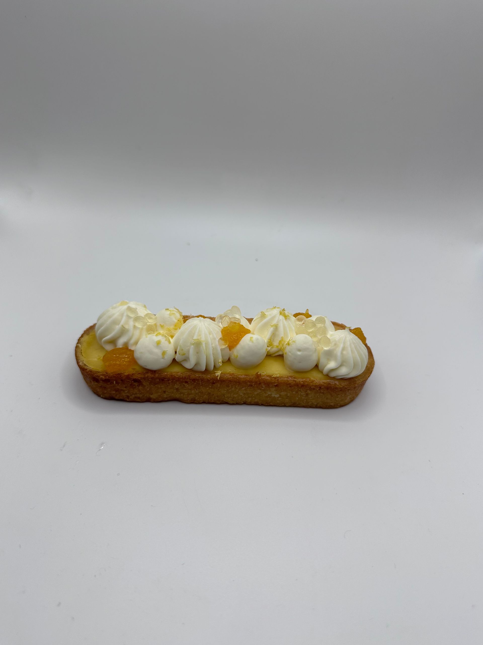 Une pâtisserie avec de la crème fouettée et des fruits sur une surface blanche.