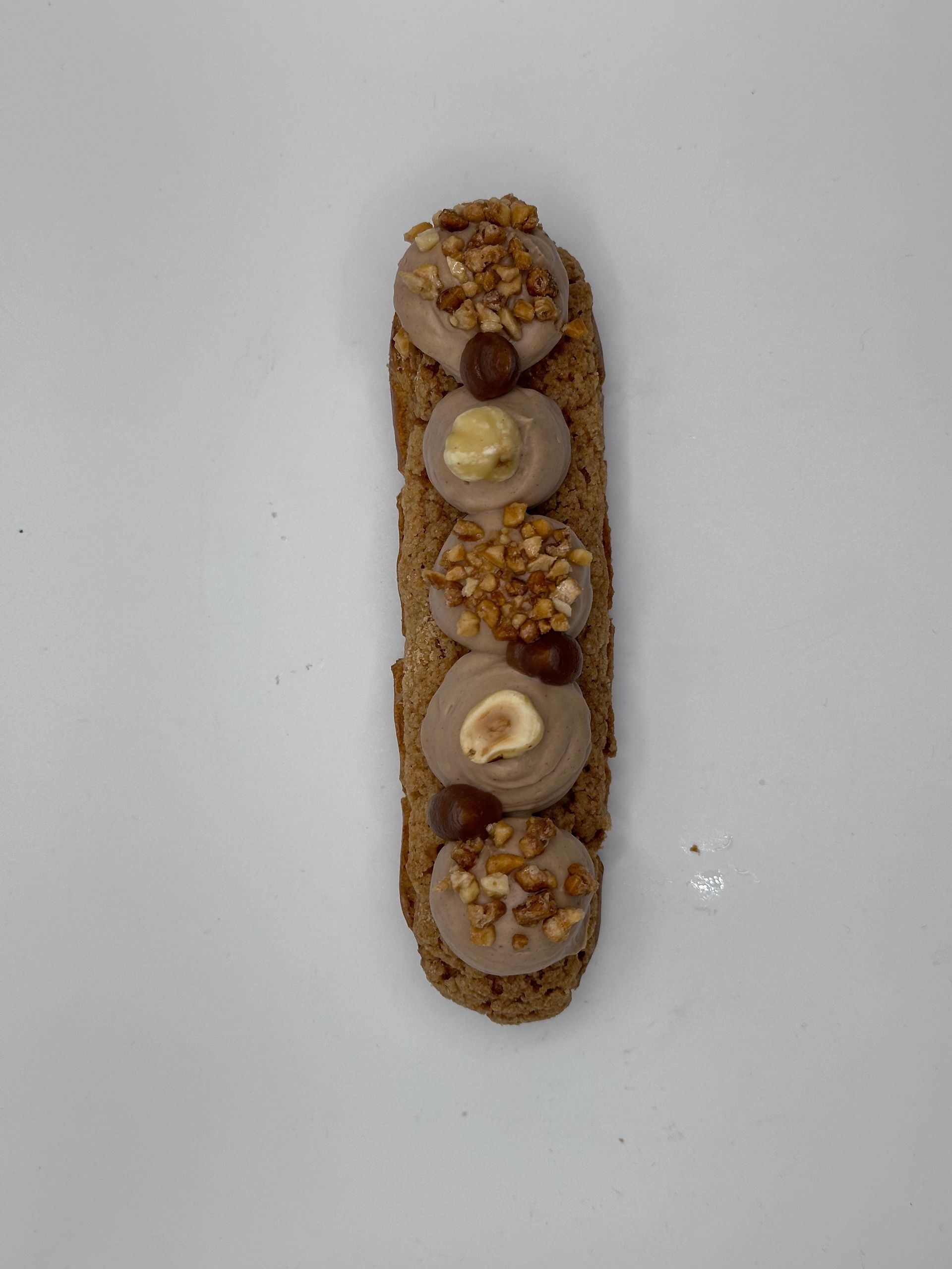 Une pâtisserie avec des noix dessus sur une surface blanche.