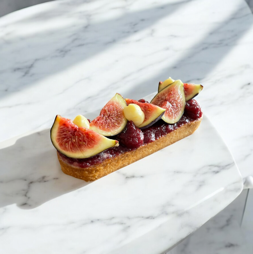 Une pâtisserie aux figues et aux cerises sur une assiette blanche