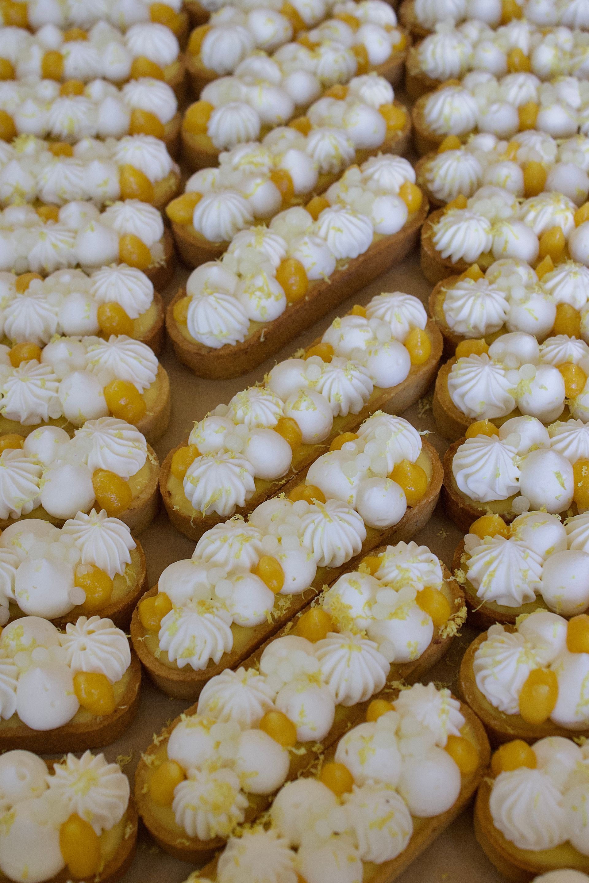 Un tas de cupcakes avec du glaçage blanc dessus sont posés sur une table.