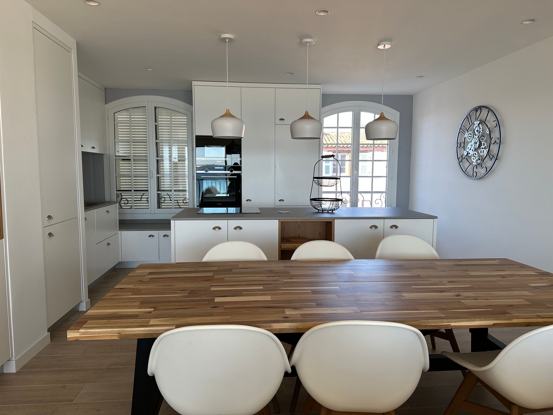 Cuisine blanche moderne avec une table à manger et des chaises en bois.