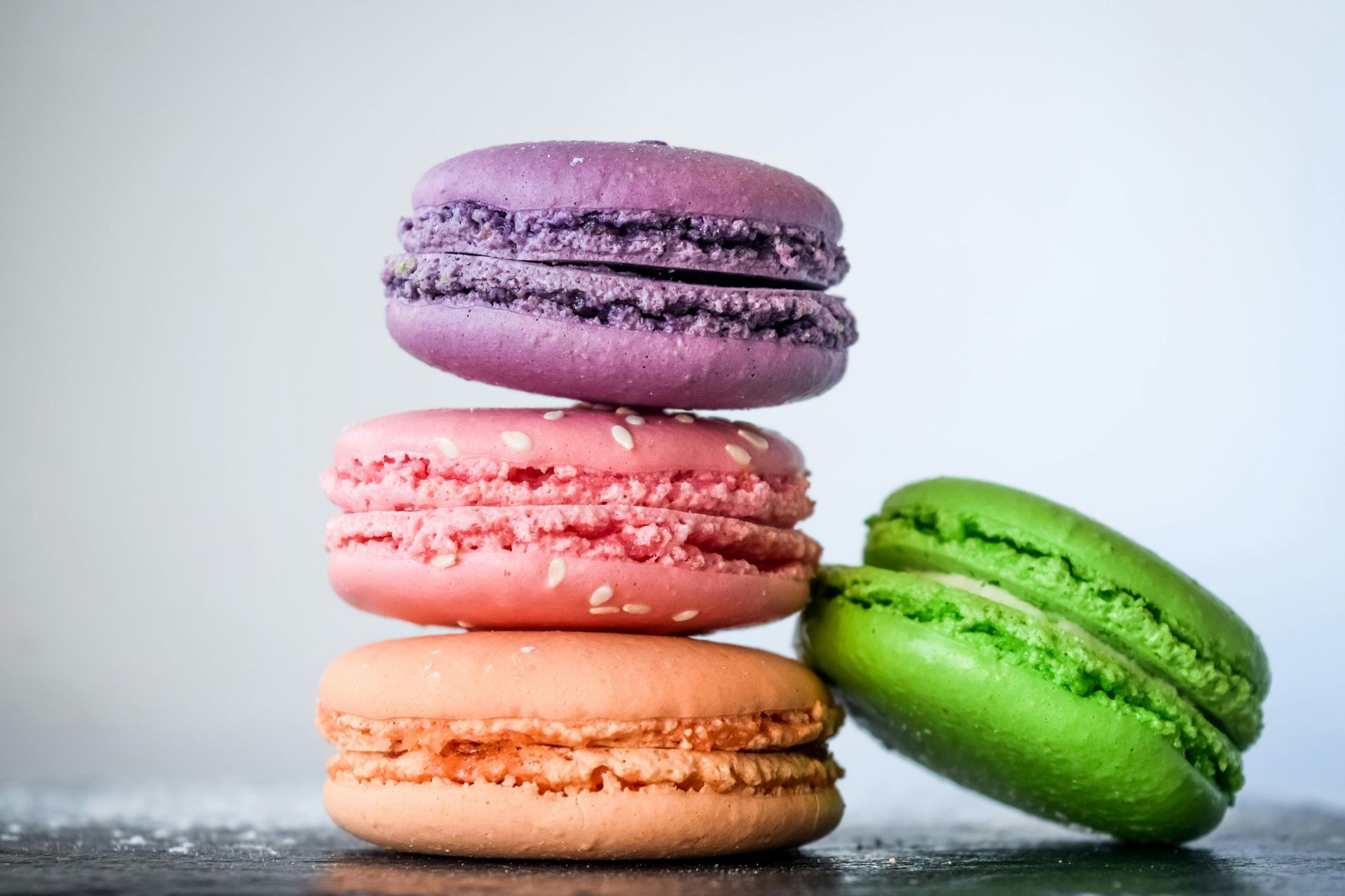 Pile de macarons colorés : violet, rose et orange, avec un macaron vert penché.