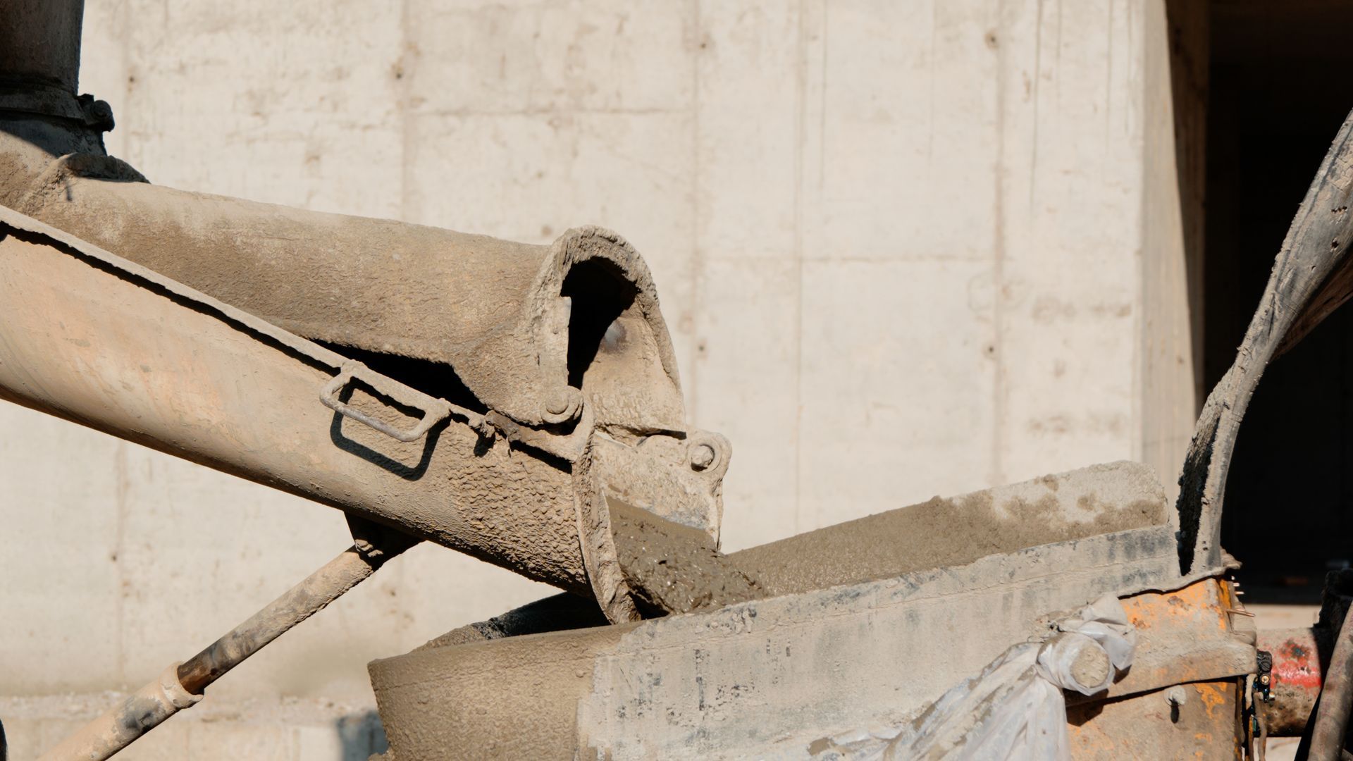 Du béton est coulé d'une goulotte de camion dans un coffrage, sur un chantier de construction.