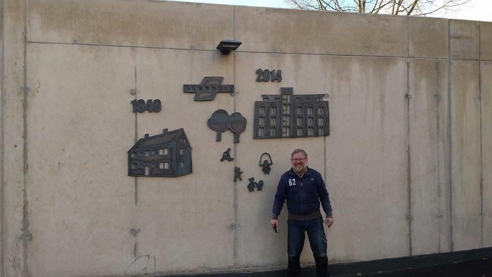 Ein Mann steht vor einer Wand mit einem Bild eines Gebäudes darauf