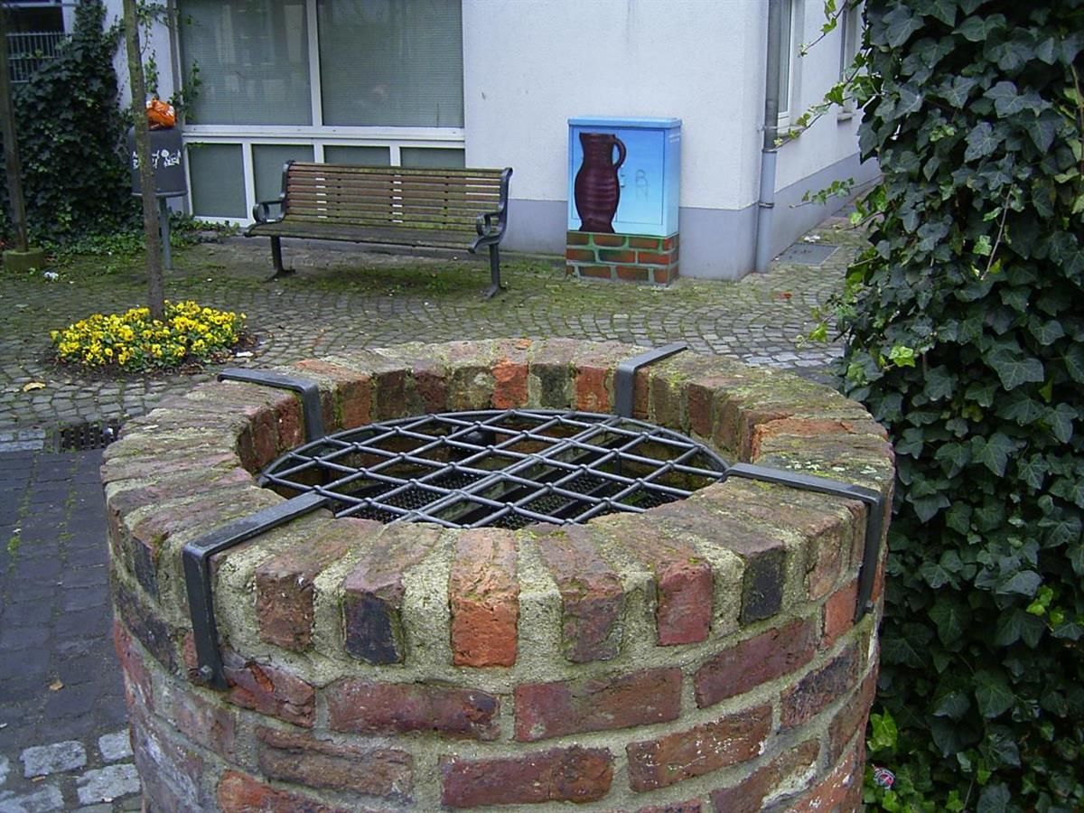 Ein gemauerter Brunnen mit einem Metallgitter darum
