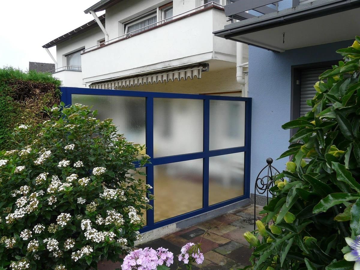 Ein Haus mit einem blauen Zaun und Blumen davor