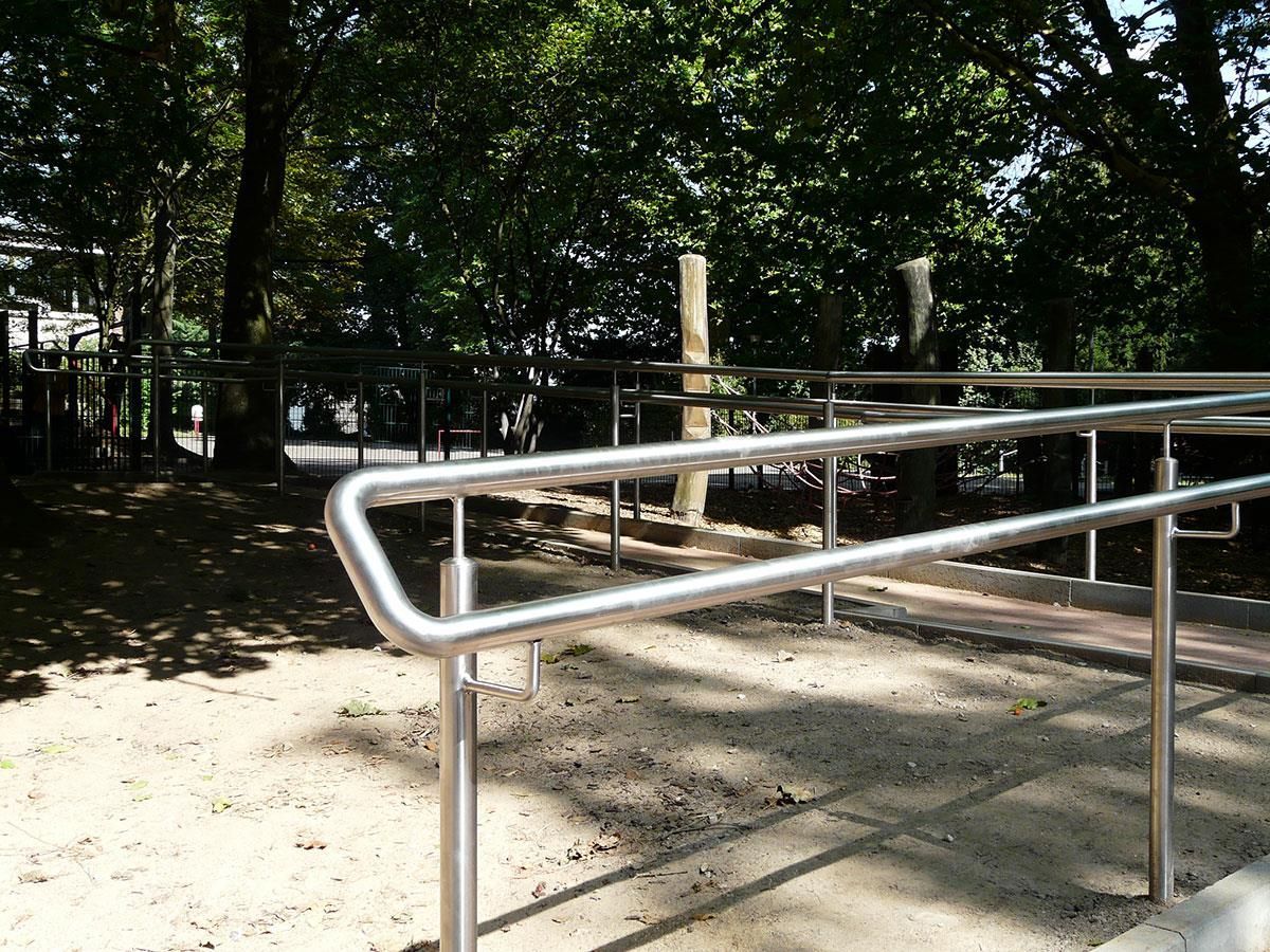 Ein Metallgeländer in einem Park mit Bäumen im Hintergrund