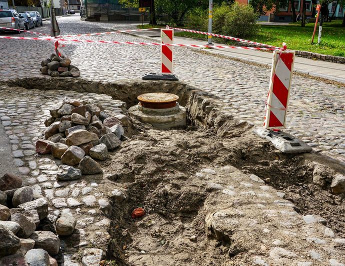 Se está instalando una tapa de alcantarilla en una calle adoquinada.