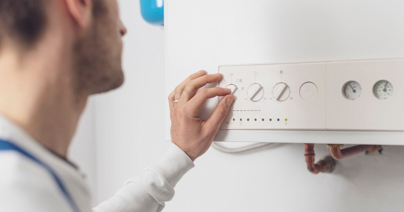 Un hombre está ajustando un termostato en una pared.