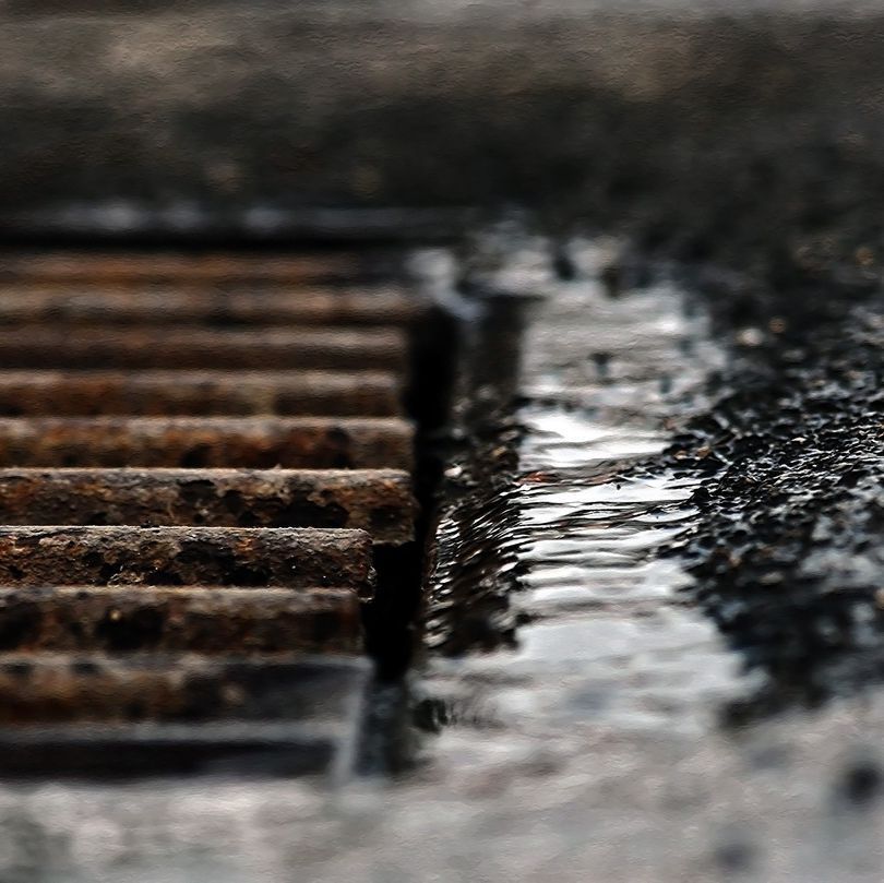 Un primer plano de una tapa de alcantarilla de la que sale agua.