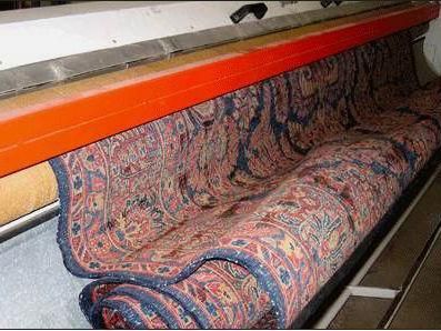 Ein Teppich wird in einer Maschine aufgerollt.