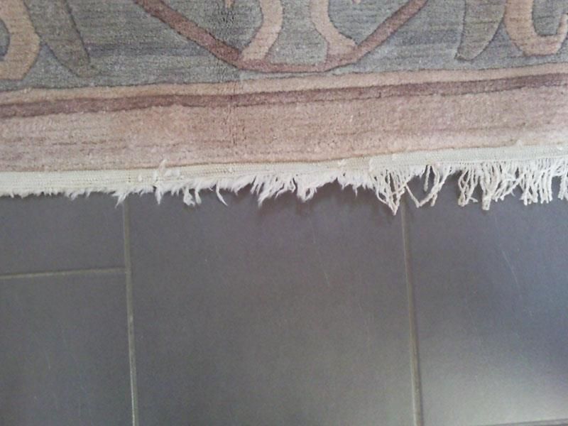 Ein Teppich mit Fransen liegt auf einem gefliesten Boden